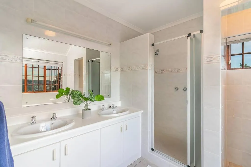 Bathroom with a double vanity, walk-in shower and a window over the hillside