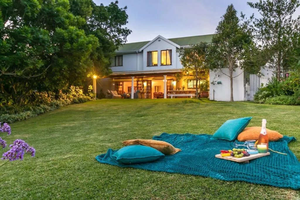 Picnic blanket set up on the lawn at dusk, with the house lit up in the background