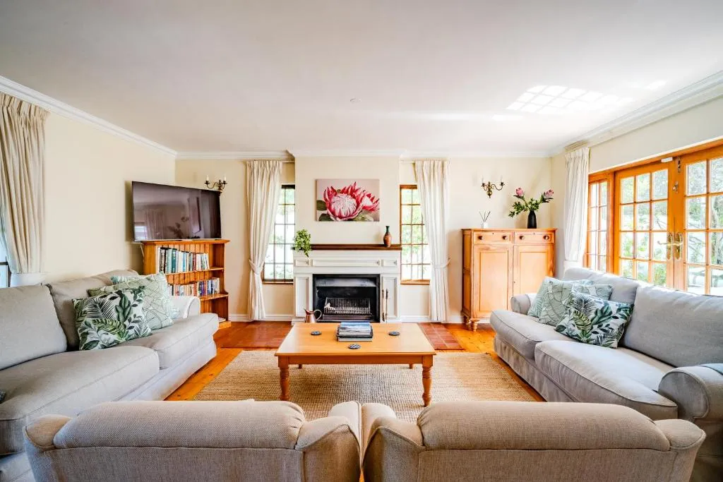 Living room with a fireplace, two large sofas and French doors onto the garden