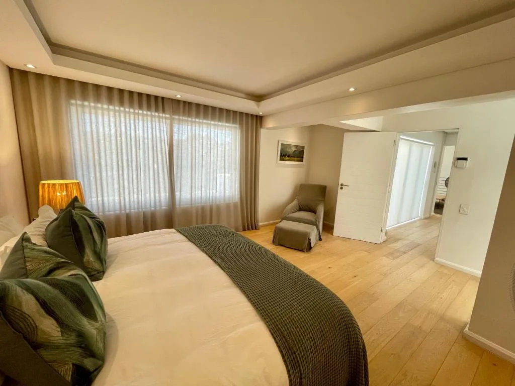 Bedroom with sheer curtains, a reading armchair and door through to the ensuite