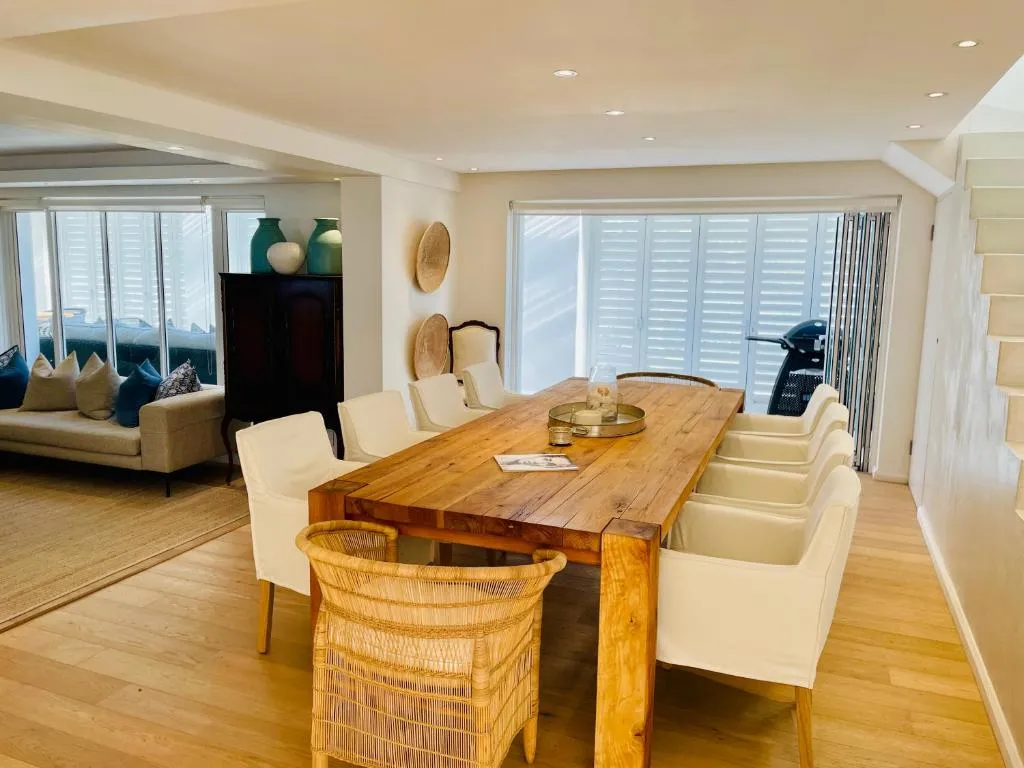 Dining room with a long reclaimed-wood table seating ten under shuttered windows