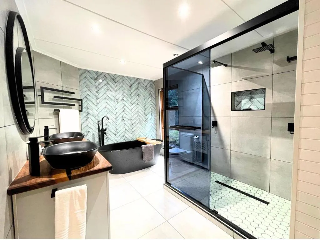 Bathroom with a freestanding stone-look tub, herringbone tile, and a glass rain shower