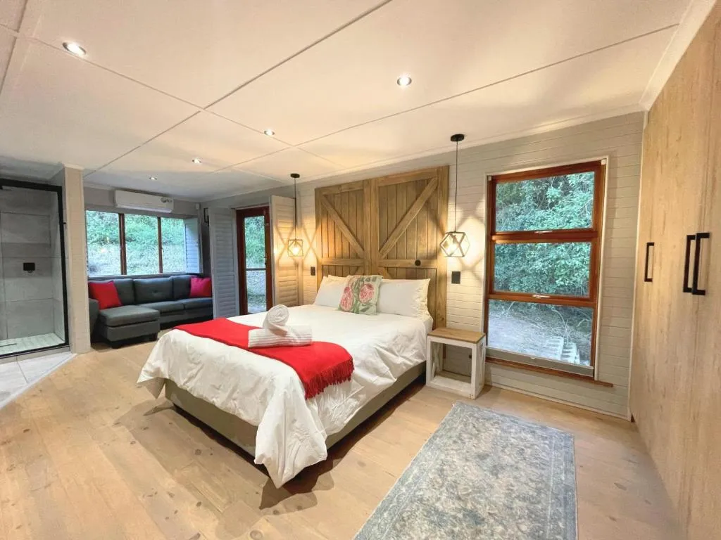 Bedroom with a barn-door headboard, red throw, and a lounge nook with a grey sofa