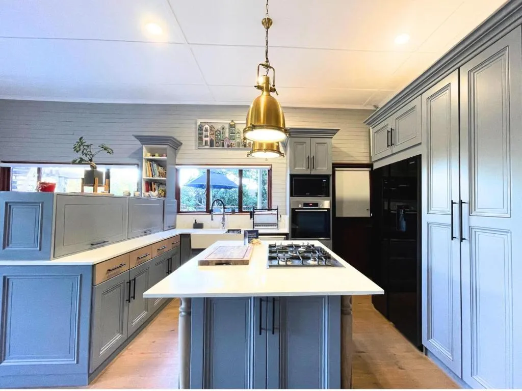 Kitchen with grey shaker cabinets, a brass pendant light, and a centre island with a gas hob