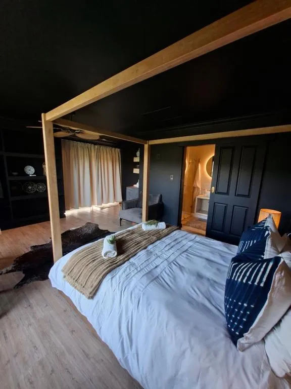 Four-poster canopy bed with dark walls and a doorway opening to the en-suite bathroom