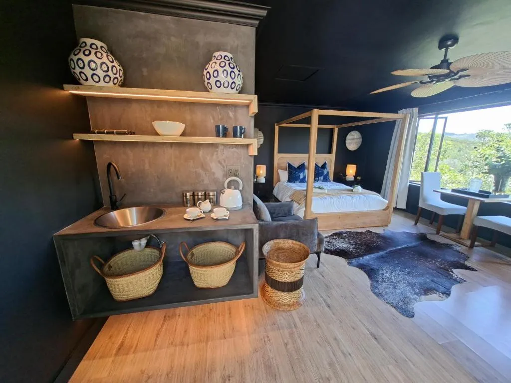 Open kitchenette with a stainless sink, kettle and woven baskets beside the bedroom
