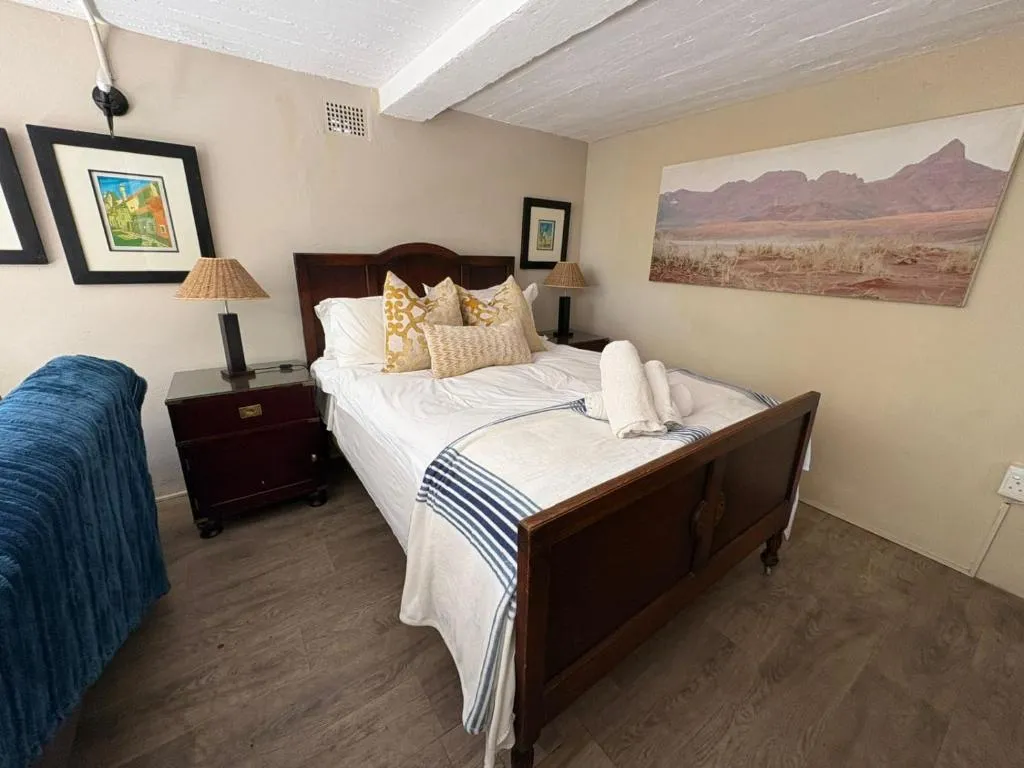 Bedroom with a dark wood queen bed, striped throw and a mountain-print artwork above the headboard