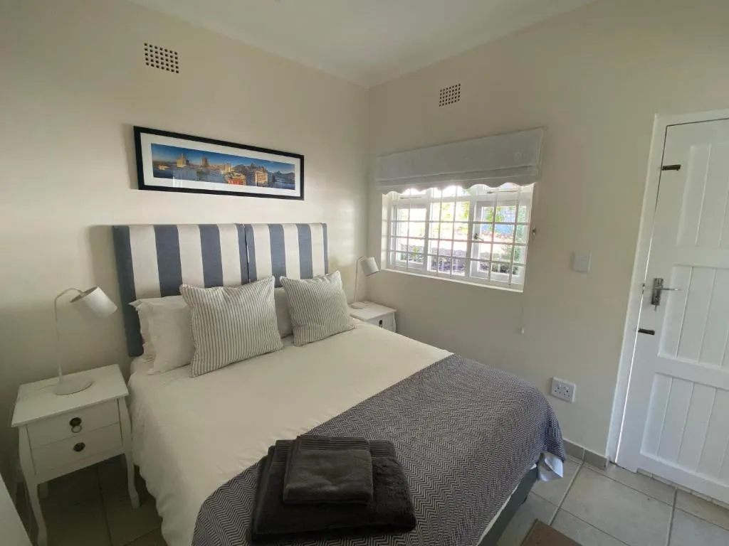 Bedroom with a blue-and-white striped headboard and a barred window looking onto a neighbouring roof
