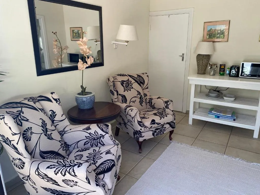 Small sitting area with floral wingback chairs, a mirror, and a console table with a microwave