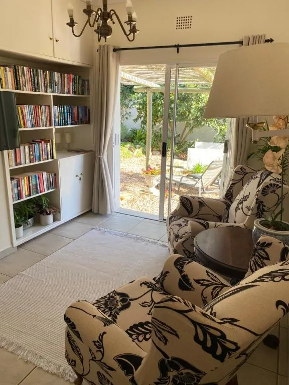 Sitting room with built-in bookshelves and sliding doors onto a paved garden patio under a pergola