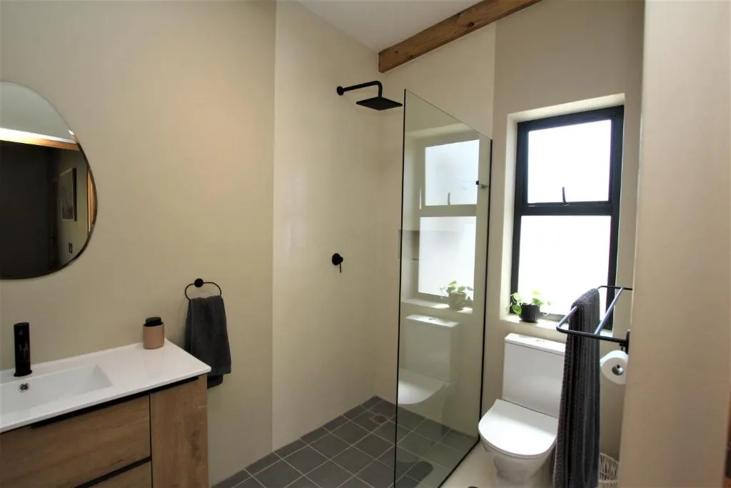 Bathroom with a walk-in glass shower, freestanding vanity and floor-to-ceiling tiling