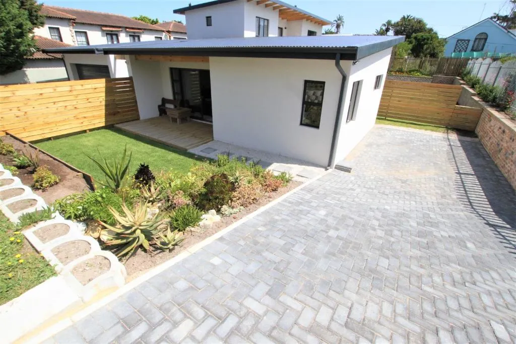 Single-storey garden flat with a covered patio, garden beds and paved driveway