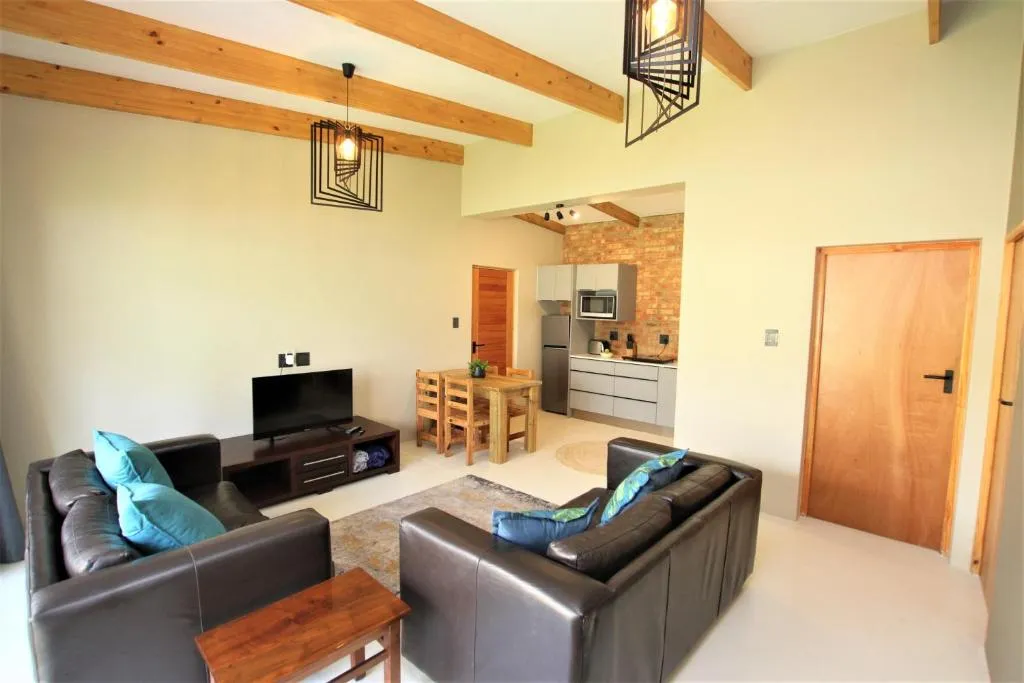 Living room with two brown leather sofas and a TV unit opening onto the kitchen