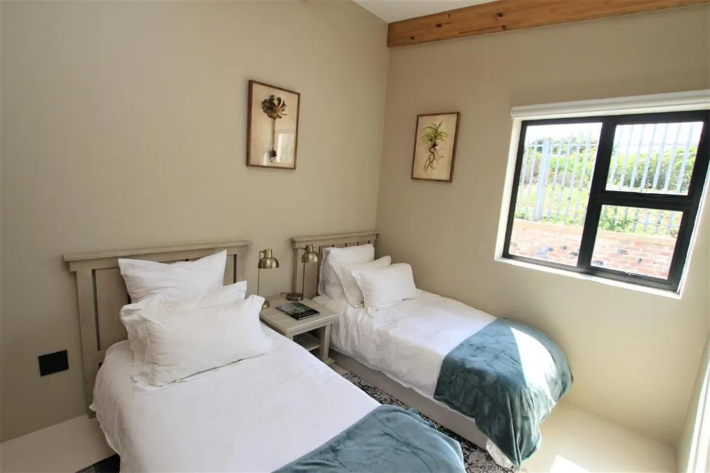 Twin bedroom with a garden-facing window and two single beds in white linen
