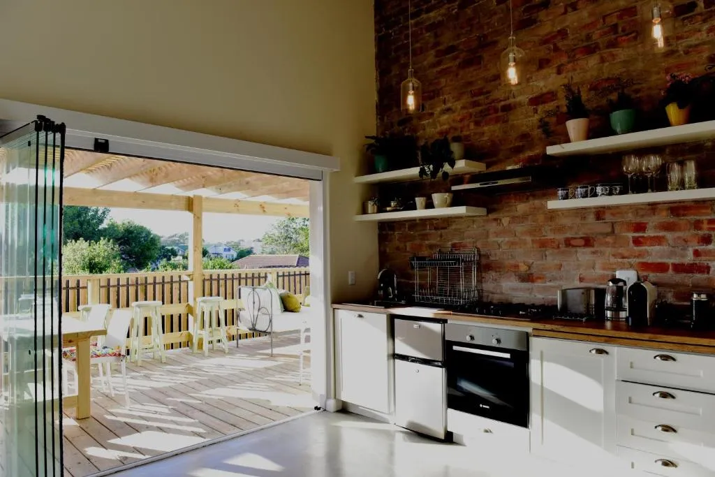 Exposed-brick kitchen with open shelving, opening directly onto the covered deck