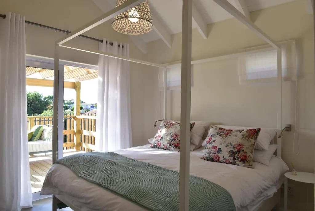 Four-poster bed beneath a vaulted ceiling with sliding doors onto a private deck