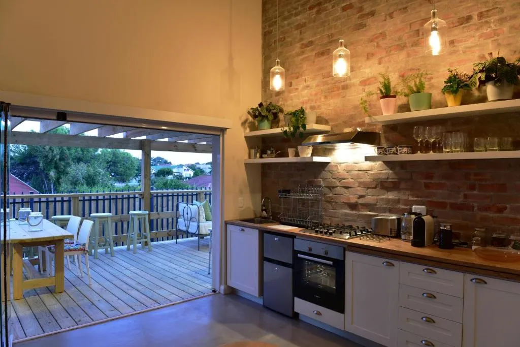 Evening view of the brick kitchen with pendant lights opening onto the deck