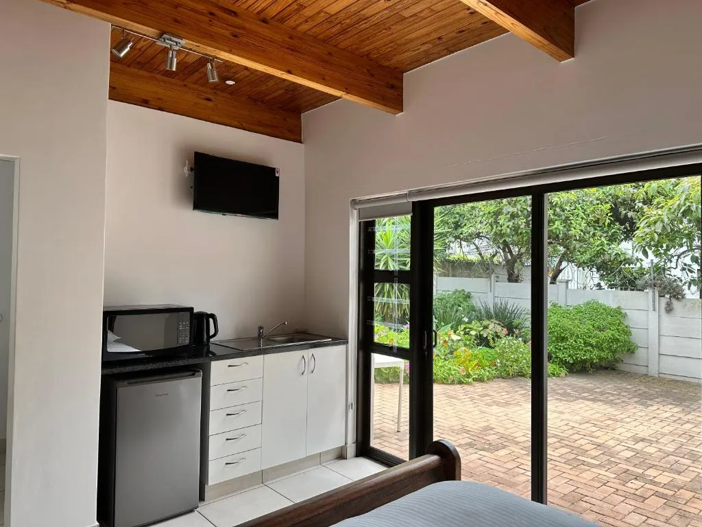 Second studio room with wood-beamed ceiling and sliding doors onto a paved courtyard