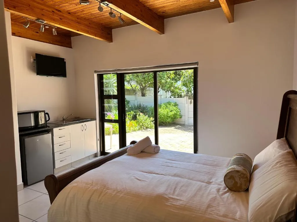 Studio room with a wood-beamed ceiling, kitchenette and sleigh bed by the garden door