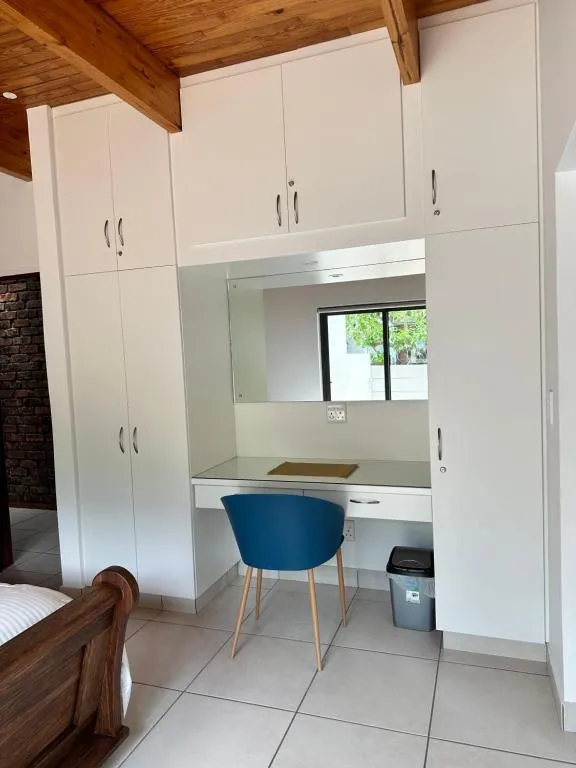 Built-in wardrobes with a mirrored dressing nook, desk and blue accent chair