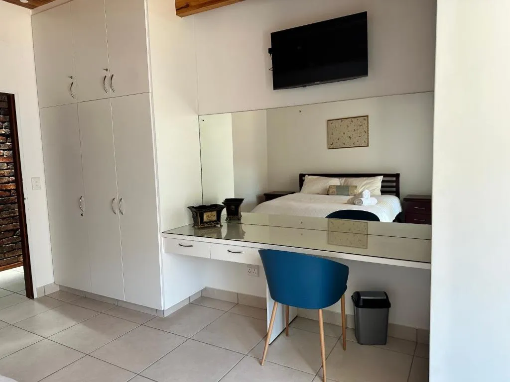 Wardrobe and dressing nook with mirror reflecting the bed and a blue accent chair
