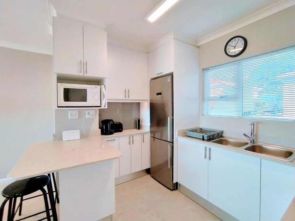 White kitchen with a stainless fridge-freezer, microwave and double stainless sink