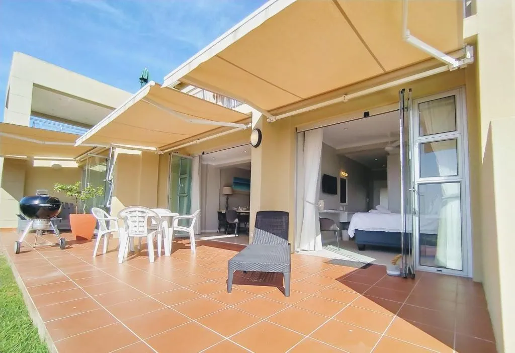 Patio with a kettle braai, dining table and chairs outside the open bedroom doors