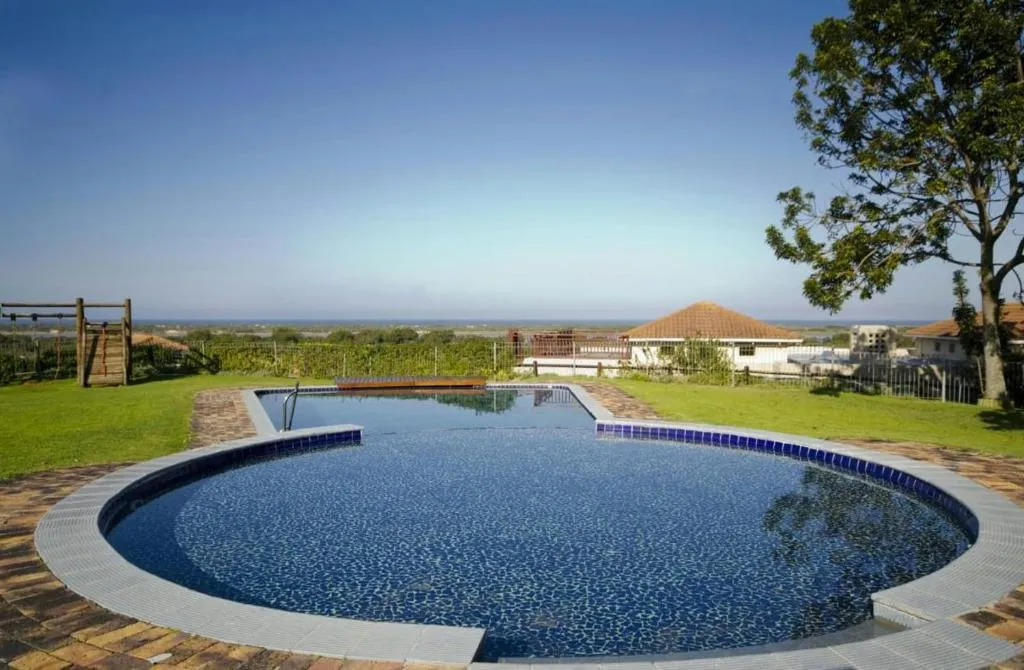 Shared pool and children's jungle gym with the sea visible beyond the garden