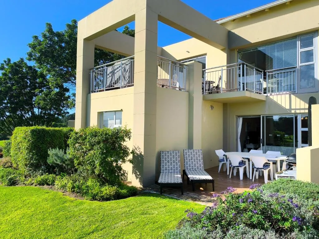Two-storey unit exterior with a covered balcony, outdoor dining table and kettle braai on the patio