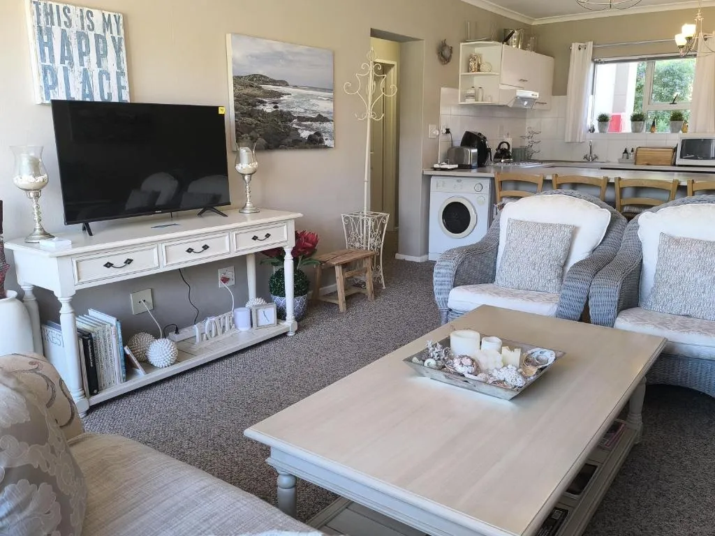 Open-plan lounge and kitchen with rattan armchairs, a television and a front-loading washing machine