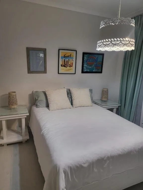 Twin bedroom with beach-themed art prints and pastel green curtains
