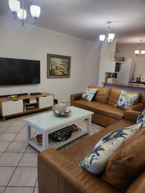 Second lounge with wall-mounted TV, wood sideboard and tan leather sectional