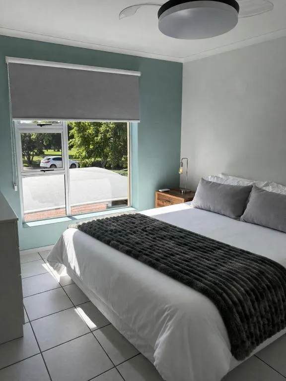 Bedroom with a sage green feature wall, faux-fur throw and street-facing window