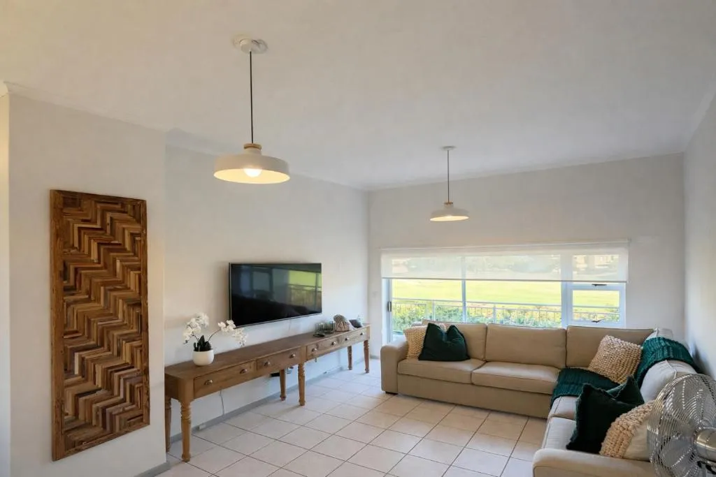 Living room with pendant lighting and a sofa facing a golf-course-view window