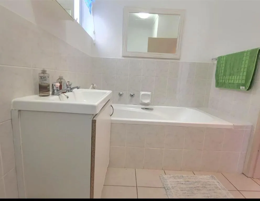 Bathroom with a corner bathtub, wall mirror and a green hand towel