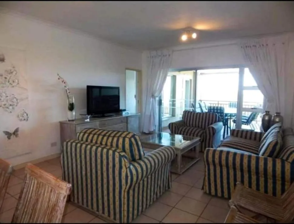 Living room with striped armchairs, a wall-mounted TV and sliding doors onto the balcony