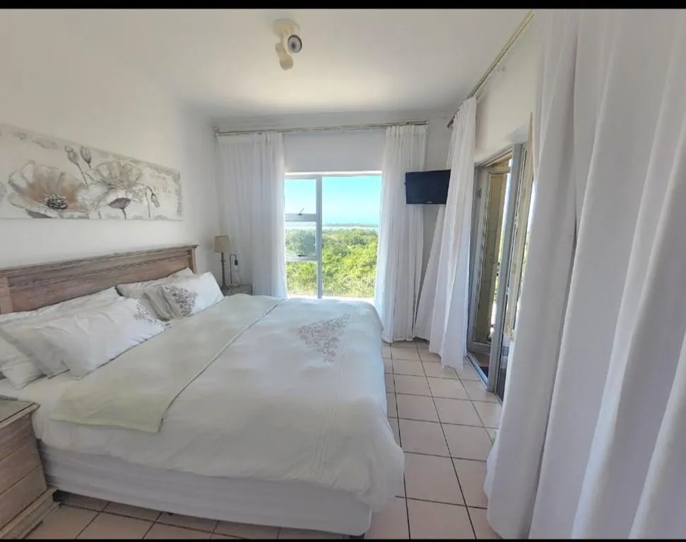 Bedroom with a wooden headboard and sliding doors opening onto a balcony with a lagoon view