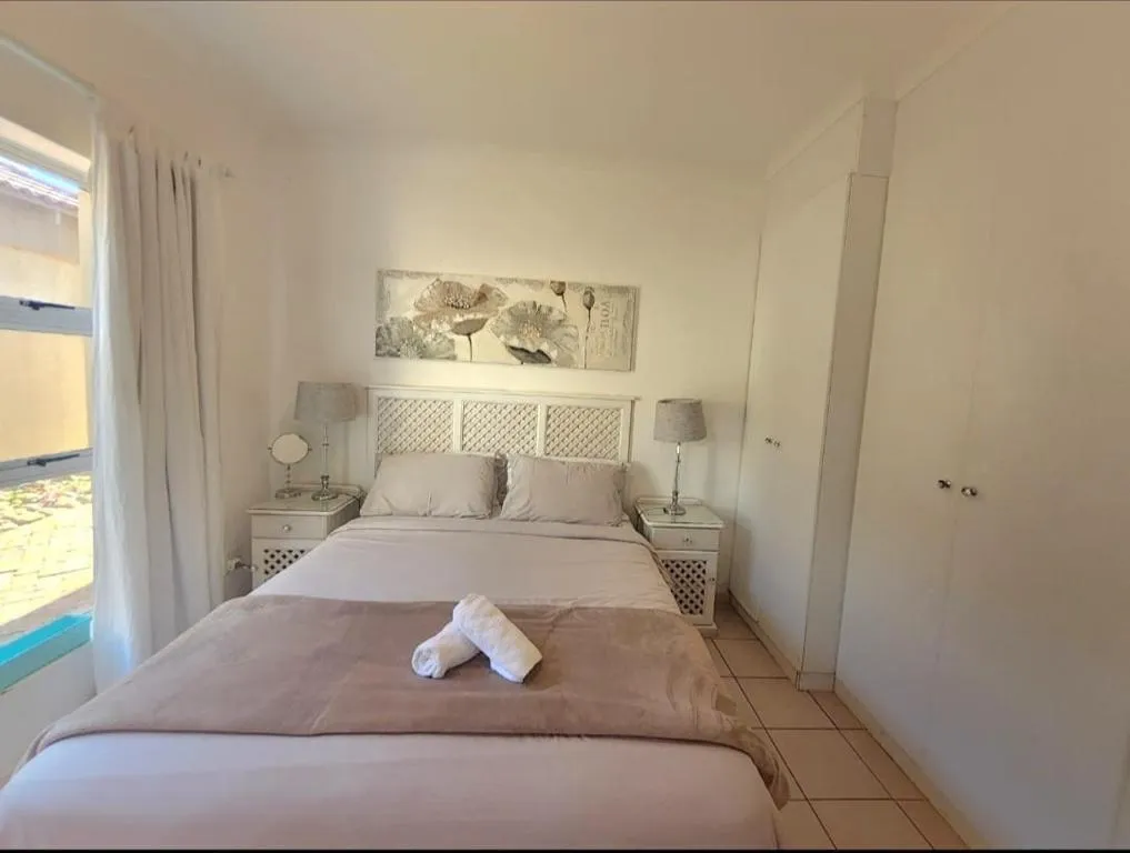 Second bedroom with a white lattice headboard, bedside lamps and a built-in wardrobe