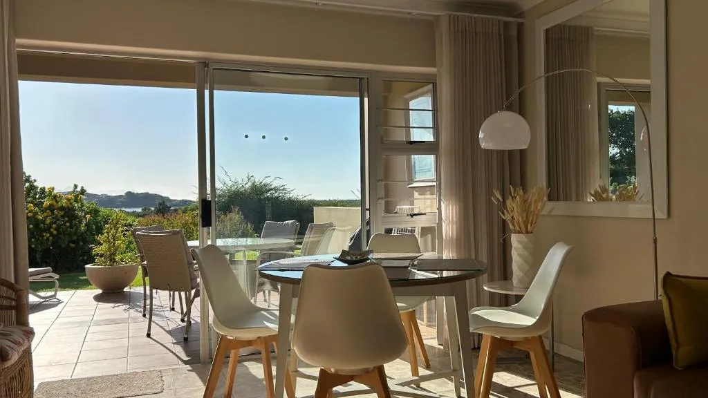 Dining table beside sliding doors framing a lagoon and mountain outlook