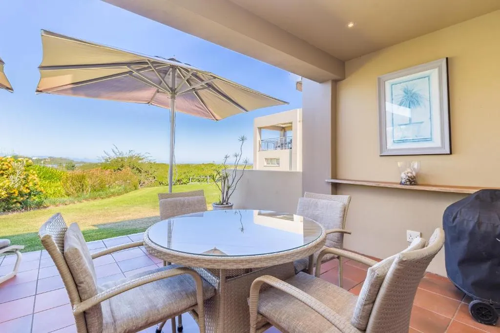 Covered patio dining table with an umbrella and a covered gas braai alongside