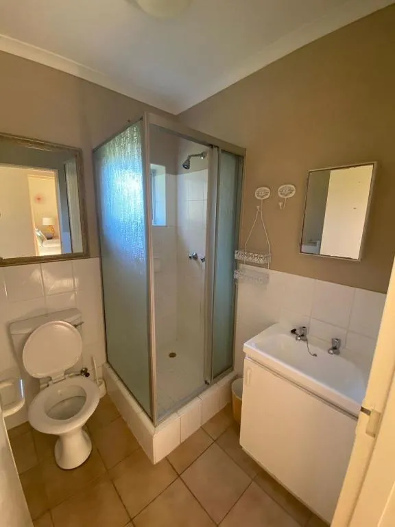 Bathroom with a corner glass shower, pedestal-style vanity and toilet