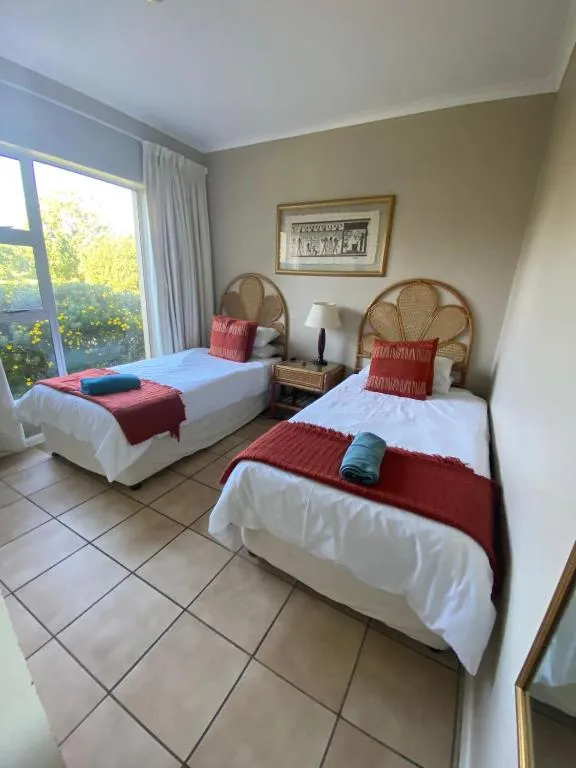Third bedroom with twin beds and rattan headboards overlooking the garden