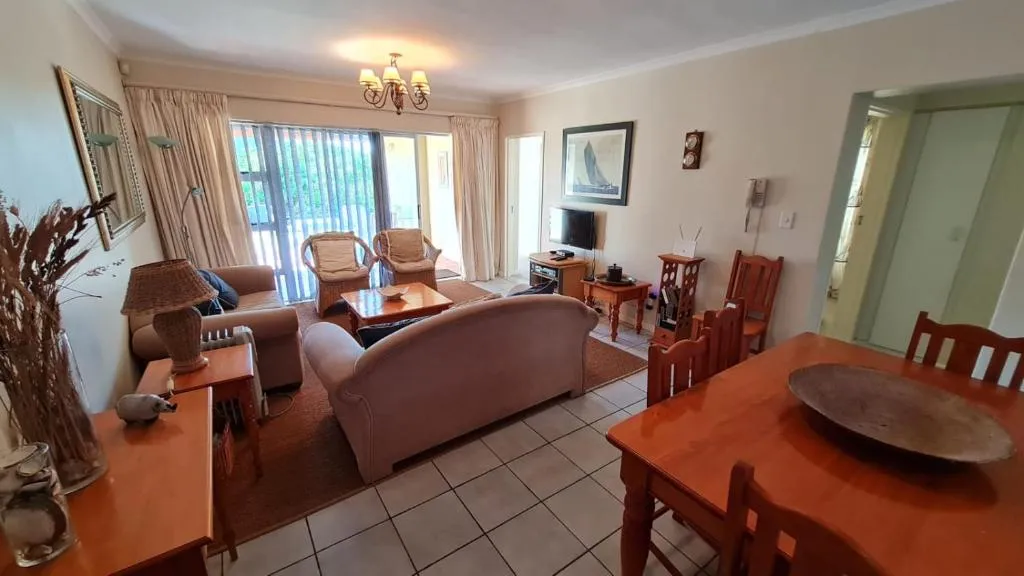 Open-plan lounge and dining area with wicker armchairs and sliding doors onto a shaded patio