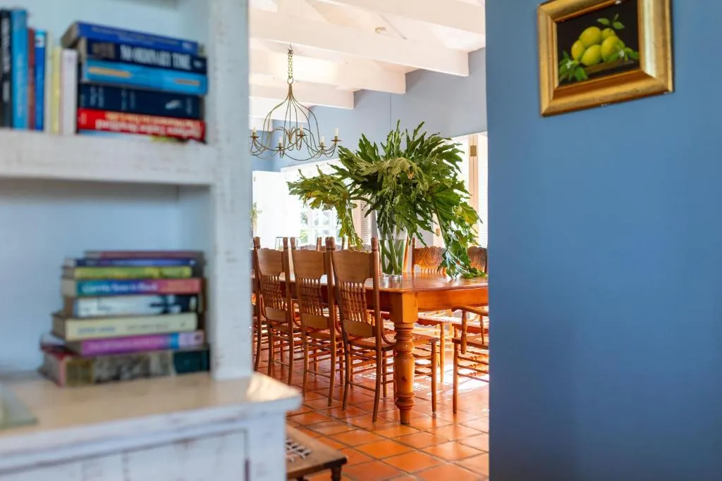 View through a bookshelf-lined doorway into the blue dining room with wooden table and chandelier