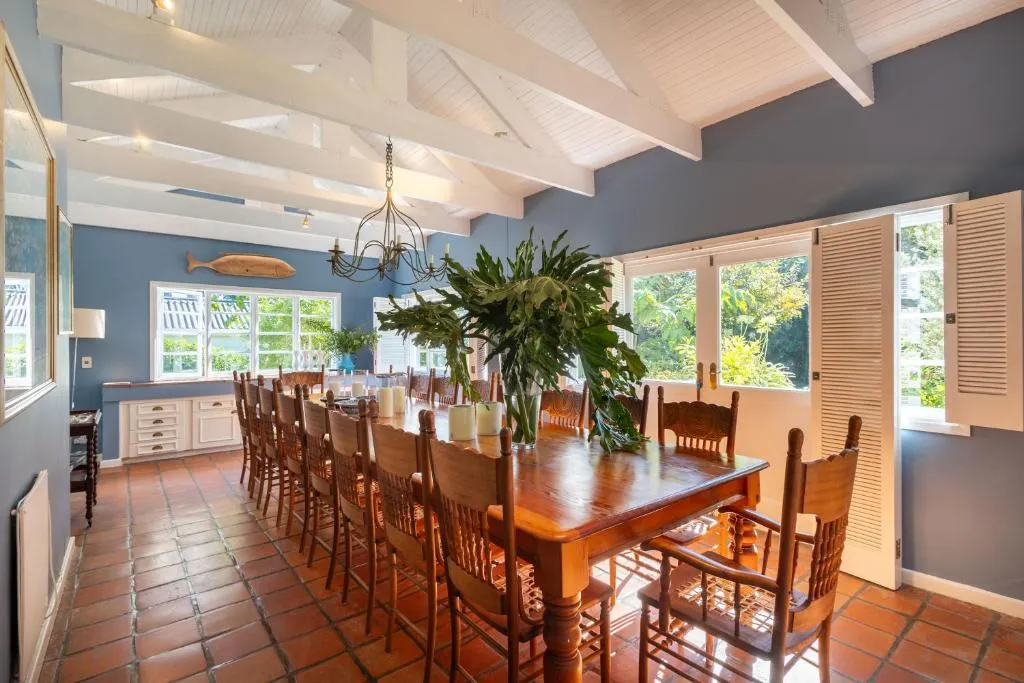 Vaulted dining room with white exposed beams, a long wooden table and French doors to the garden