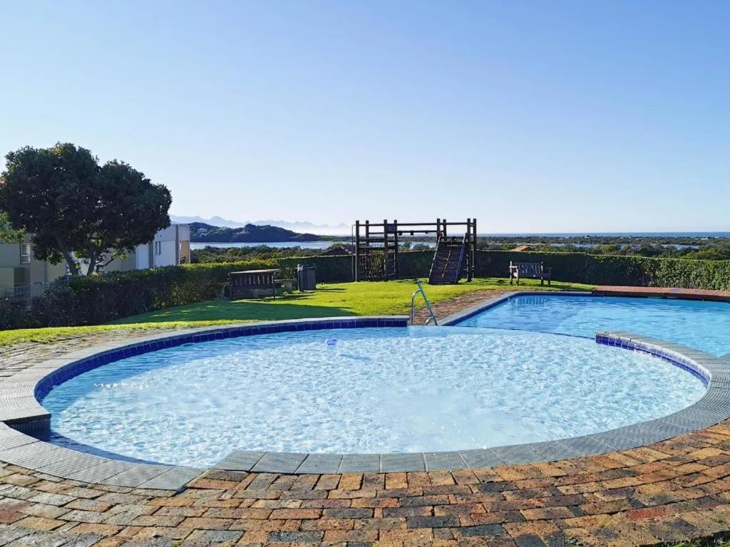 Round communal pool on the estate lawn with a children's climbing frame nearby