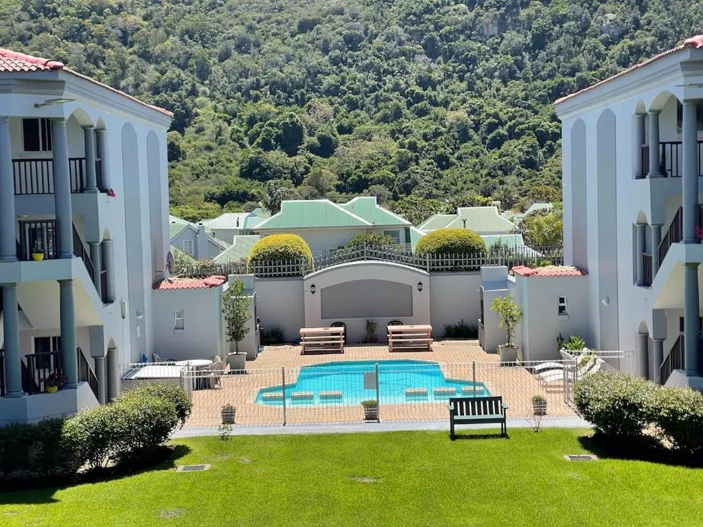 View from the balcony over the shared courtyard pool, with wooded hillside rising behind the buildings