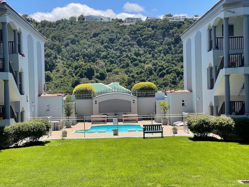 Second-floor view over the shared pool courtyard with hillside homes visible in the distance