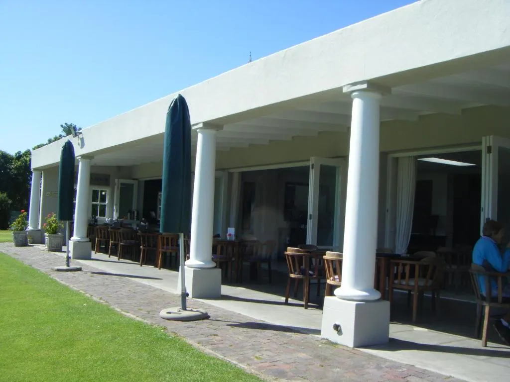 Colonnaded golf clubhouse terrace with umbrella-shaded tables at the estate