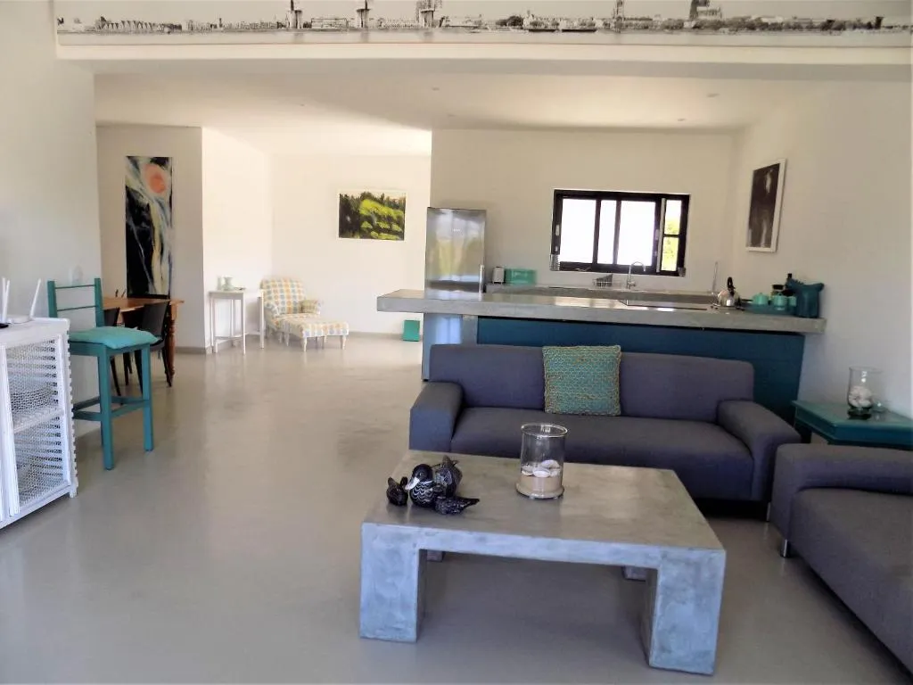 Open-plan living area with grey sofas, a concrete coffee table and kitchen island beyond